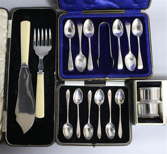 Two cased sets of six silver teaspoons, one with tongs, a cased set of silver fish servers and cased pair of silver napkin rings.